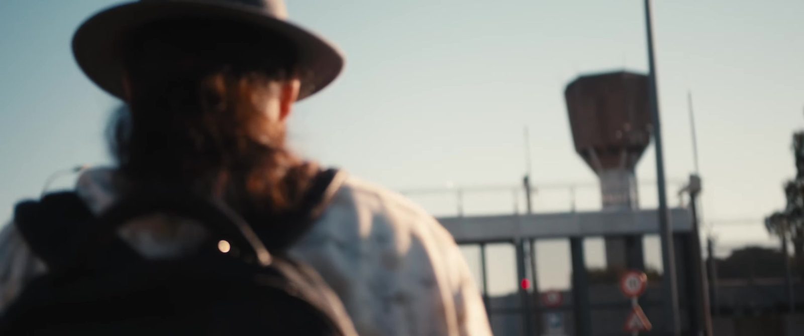 Man with a hat walking towards the prison – still from Let It Out – Rap Music in Prison